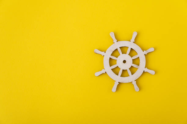 White steering wheel on yellow background. Marine theme. Yacht management. Copy space.