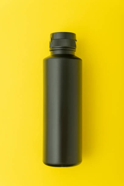 istock Black plastic bottle vial on yellow background. Mock up. 1299497159
