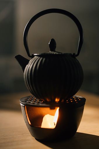 Picture of glass teapot with ceramic cup of green tea on dark background. Hot chinese green tea. Hot food and healthy meal concepts.