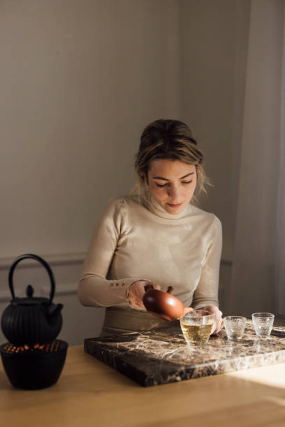 istock Traditional Tea Making: a Beautiful Young Blonde Woman Making Herself Tea 1299498424