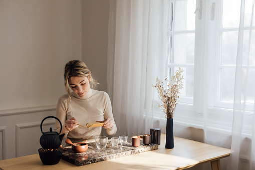 Slow living rituals: a young woman enjoys a moment of peace while making herself green tea.