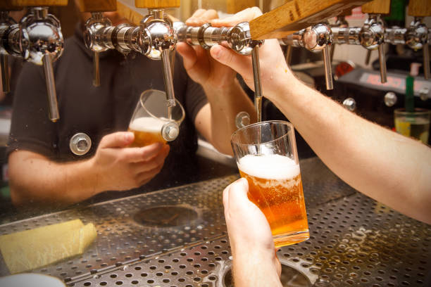 istock Close-up of bartender pouring draft beer in glass 1299504467