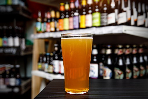 Glass of craft beer at the bar. Assortment of bottles on a blurred background