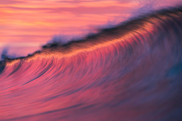 Cresting wave breaking in brilliant orange and golden morning light
