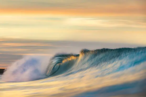 Photo of Cresting wave breaking in brilliant orange and golden morning light