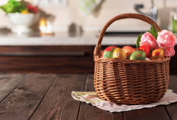 istock Wicker basket with Easter colorful eggs and peonies on kitchen wooden table. Spring Easter composition. Copy space for text or design. 1299510151