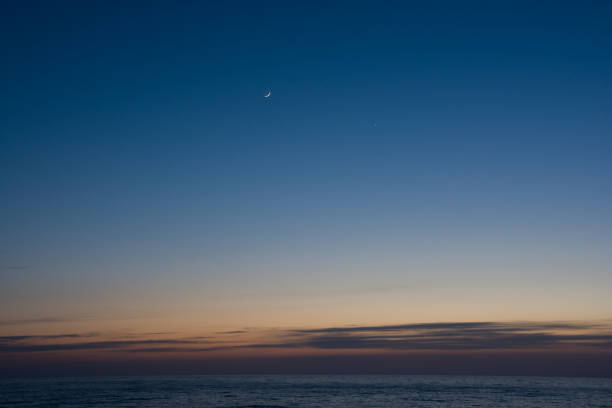 istock Quiet sea dusk and crescent moon 1299510796