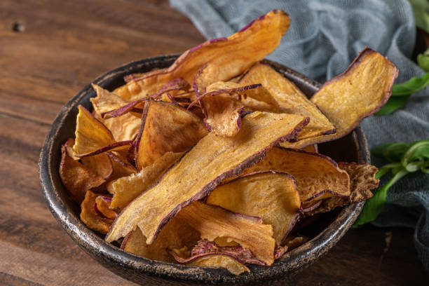 istock Delicious sweet potato chips in bowl, on table. 1299510856