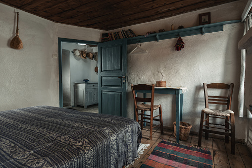 Traditional interior of old bedroom with handmade wooden furniture and traditional  folk ornament textile in historic country village house