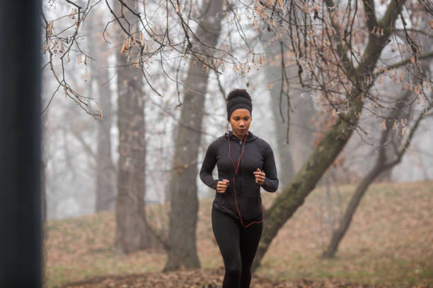 istock Lovely Afro-American lady is jogging in misty forest. 1299518128