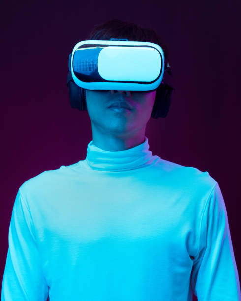 istock Young asian man wearing virtual reality goggles watching 360 degree video in neon light, Technology concept 1299518972