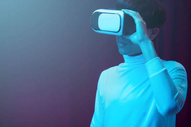 istock Young asian man wearing virtual reality goggles watching 360 degree video in neon light, Technology concept 1299518975