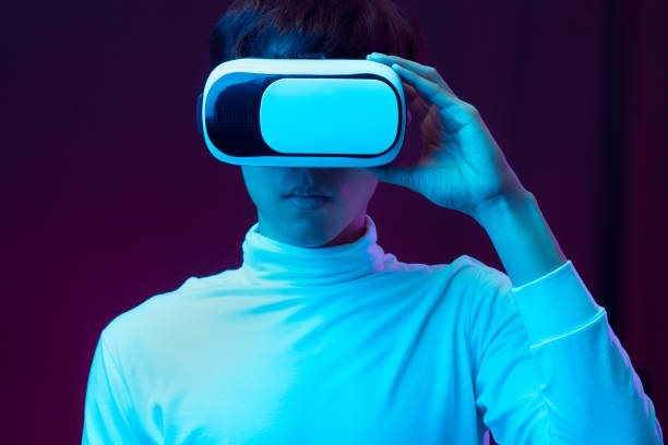 istock Young asian man wearing virtual reality goggles watching 360 degree video in neon light, Technology concept 1299518978