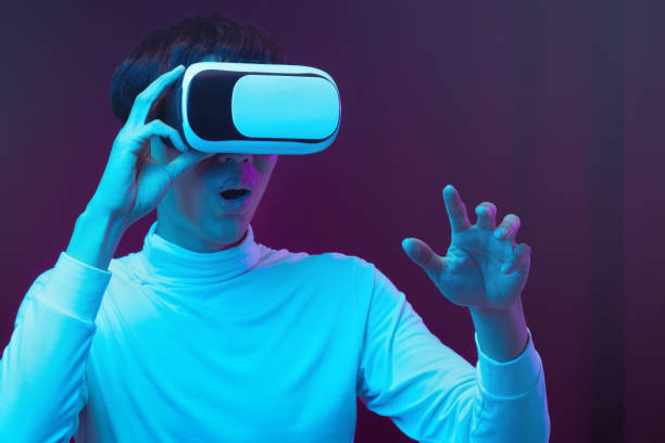 Excited asian young man wearing VR headset in neon light, Future technology concept