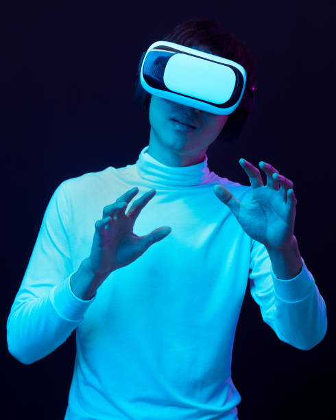 istock Young asian man wearing virtual reality goggles watching 360 degree video in neon light, Technology concept 1299519001