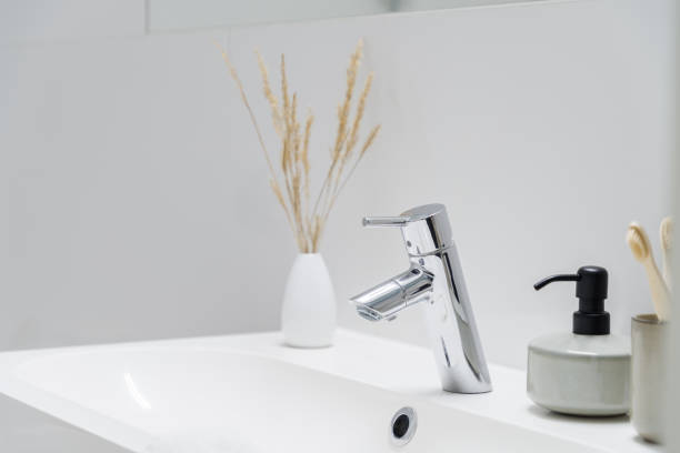 istock Simple silver tap in bathroom washbasin, close-up 1299523573