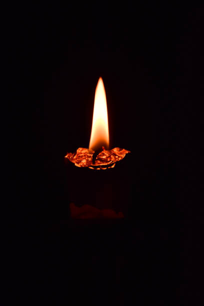 istock A melted candle burning in the dark. On a dark background. Close-up shot. 1299529690