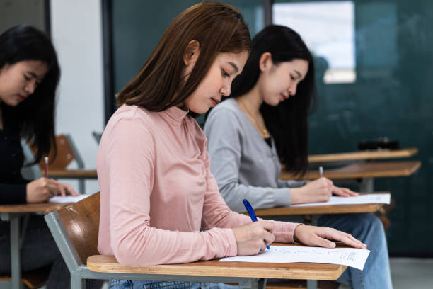 istock Young female university students concentrate on doing examinations in the classroom. Girl students seriously write the exercise of the examinations in the classroom. 1299529745