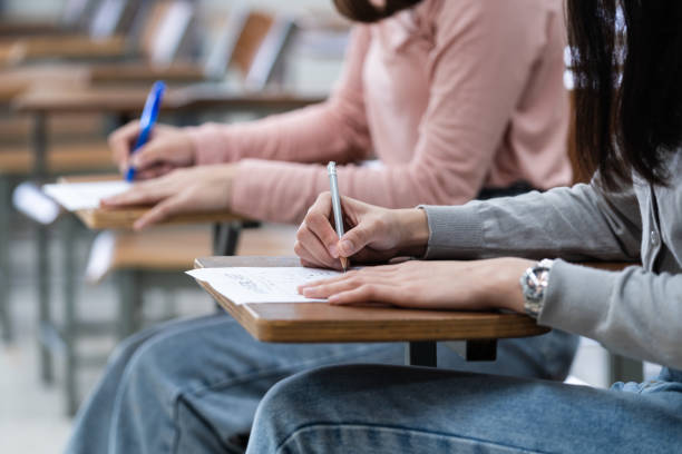 istock Young female university students concentrate on doing examinations in the classroom. Girl students seriously write the exercise of the examinations in the classroom. 1299530379