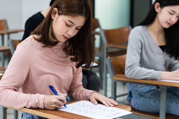 istock Young female university students concentrate on doing examinations in the classroom. Girl students seriously write the exercise of the examinations in the classroom. 1299531251