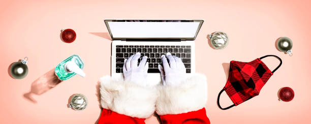istock Santa Claus using a laptop computer with a mask and a sanitizer bottle 1299531394