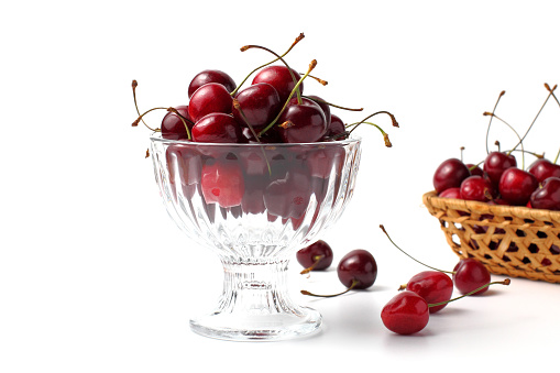 cherries in a glass vase on white, concept for a banner or flyer to advertise healthy food and fruits.