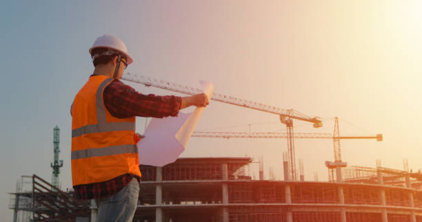 istock Asian engineering wearing hardhat and holding blueprint for working at construction on site 1299533561