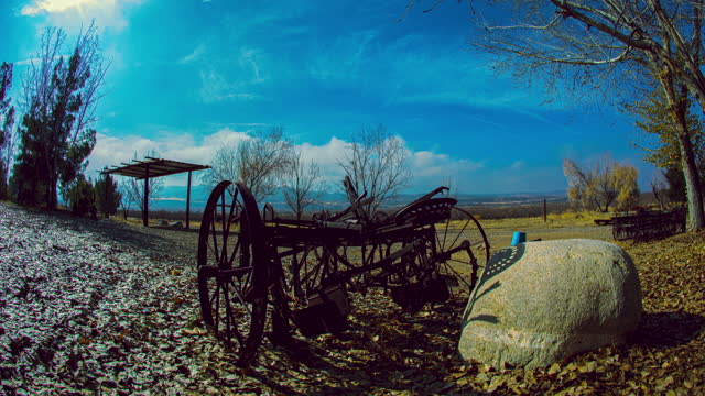 Rolling clouds over farmland with old, rusty plow