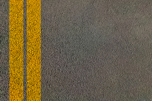 Road dividing yellow lines on asphalt Highway background painted for transport traffic control and guide vehicles for man movement during drive top view of Road with two lanes.