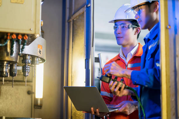 istock Male Asian engineer professional  having a discussion standing concult cnc machine in the factory ,two asian coworker brainstorm  explaining and solves the process of the cnc operate machine 1299548054
