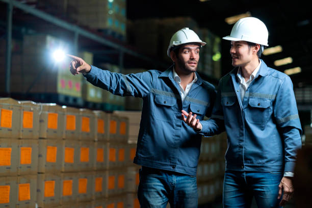 istock successful engineer teamwork casual positive converation working together in warehouse factory.Male worker with safety helmet checking quantity quality of product boxes on storage shelf in warehouse 1299548078