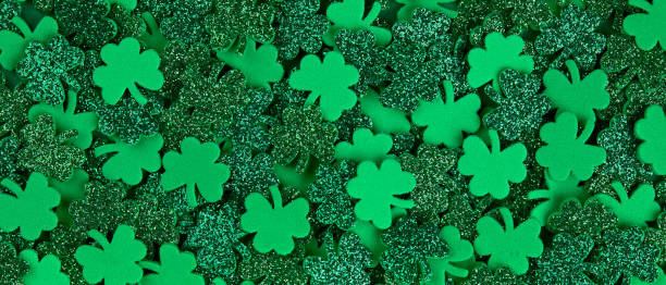 istock Shamrock confetti texture background banner filled with green lucky clovers 1299549299