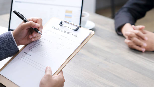istock Businessman hand checking the interview evaluation paper for job interview at office background, job search, business concept 1299550175