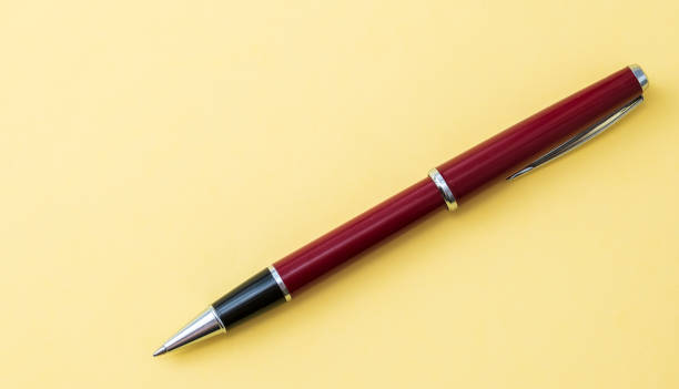 istock red ballpoint pen lies on a yellow background 1299552634