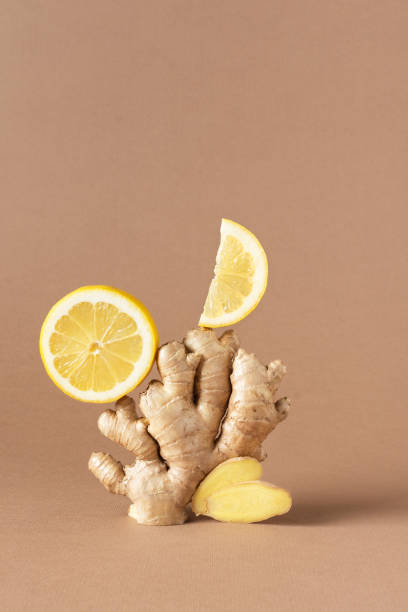istock Composition of fresh ginger root and lemon over light brown background. 1299553565
