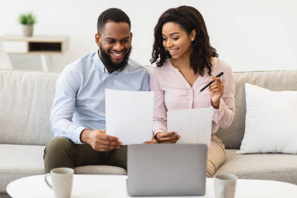 istock Cheerful black couple reading documents at home, checking bills 1299554954