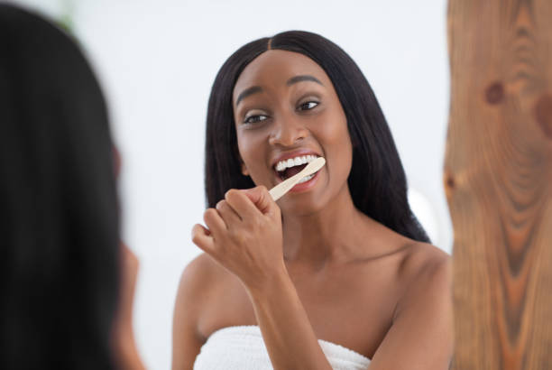 istock Cheerful young african american female brushing teeth with toothbrush 1299555677