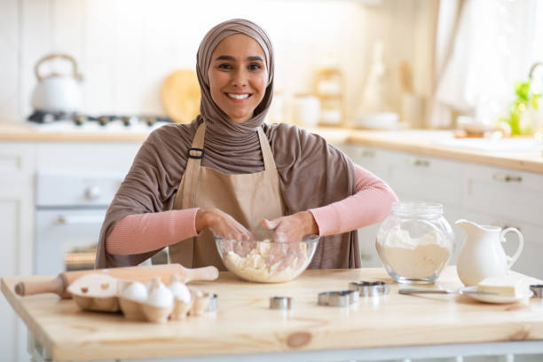 istock Smiling Muslim Lady In Hijab Baking In Kitchen, Kneading Dough 1299555696
