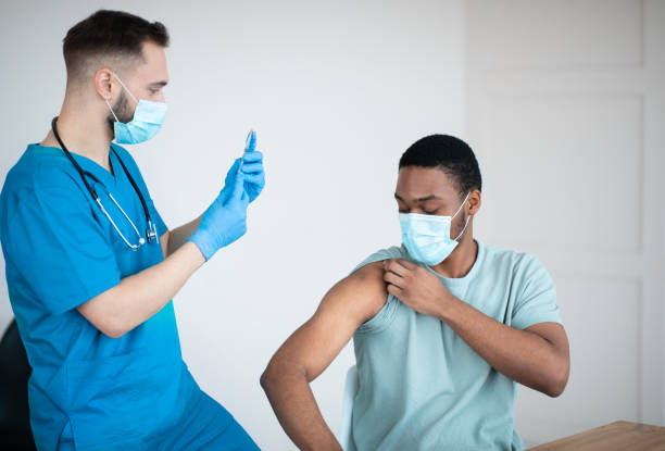 istock Covid-19 vaccination program. Black male patient getting coronavirus vaccine shot on visit to physician at health centre 1299556064