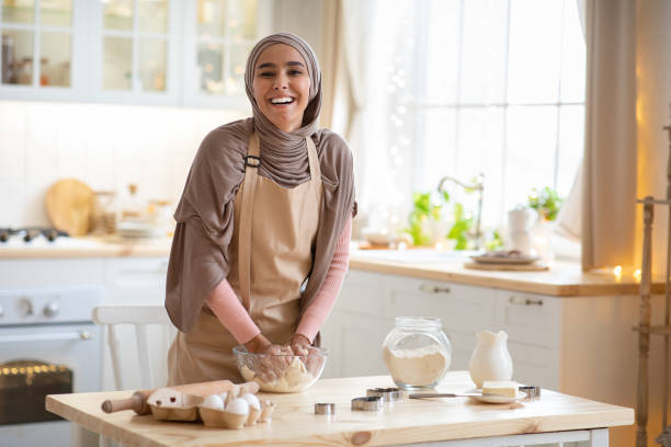 istock Baking Concept. Joyful Muslim Woman In Hijab Kneading Dough In Kitchen Interior 1299556817