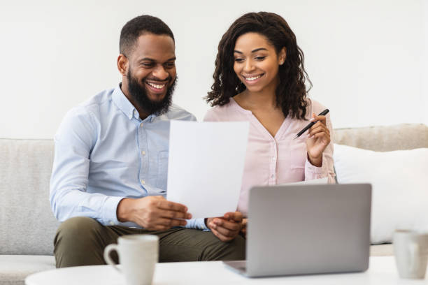 istock Cheerful black couple reading documents at home, checking agreement 1299557091