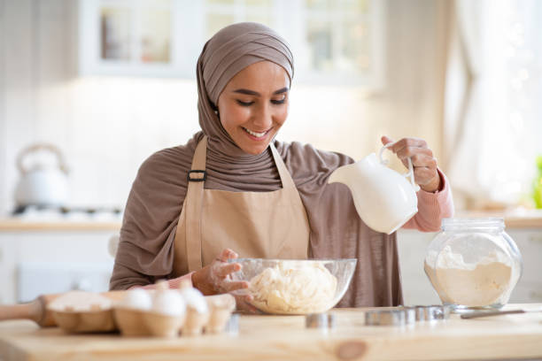 istock Home Bakery. Beautiful islamic lady in hijab preparing dough for pie 1299557359