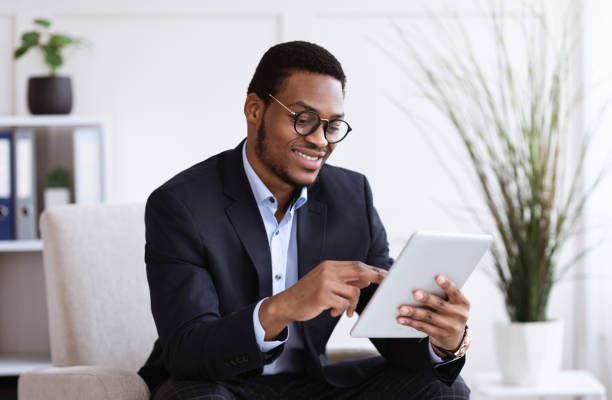 istock Happy african american young businessman using digital tablet in office 1299558439
