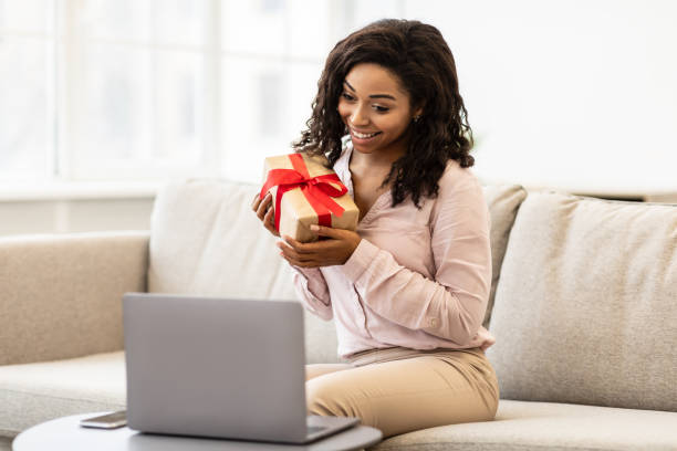 istock African American Woman Holding Present Box Using Laptop 1299558676