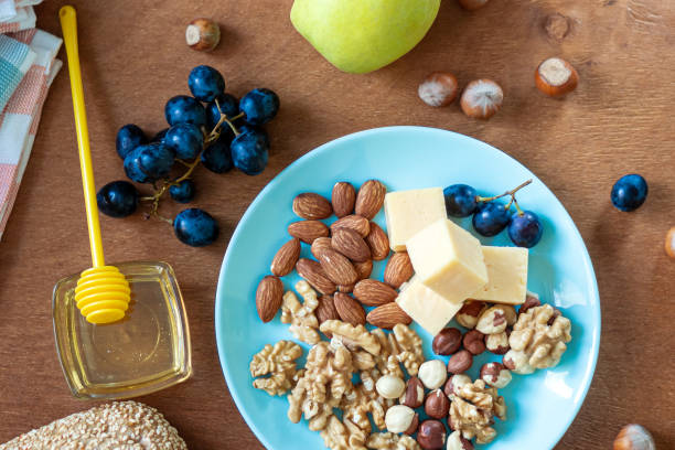 istock Top view, nuts and cheese in a blue plate on a wooden board. 1299560101