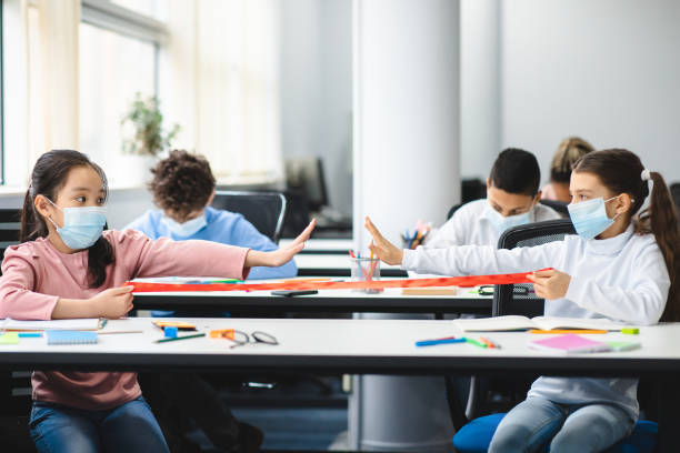 istock Diverse pupils wearing face masks keeping distance at arm's length 1299560176