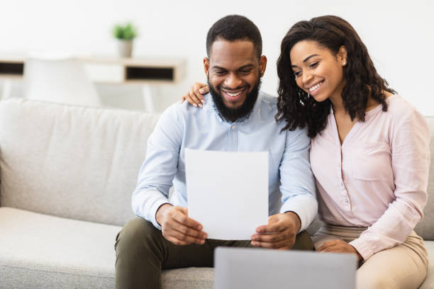 istock Smiling black couple reading documentation at home, checking agreement 1299560420