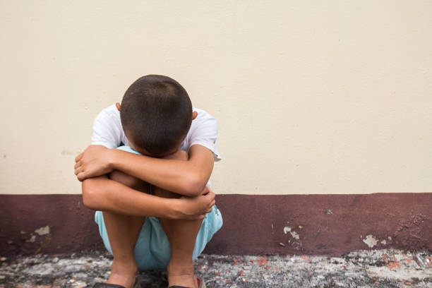 Sad little boy sitting on floor in empty room.taken with copy space.