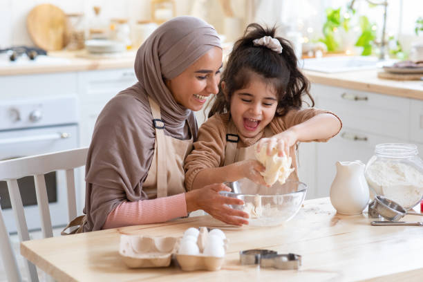 muslim mom and daughter having fun at home, baking in kitchen together - hijab imagens e fotografias de stock