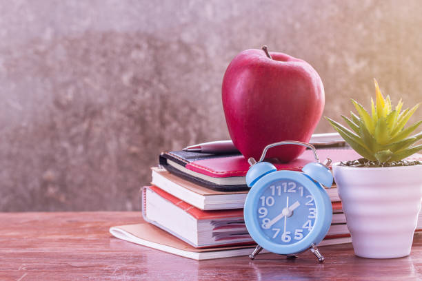 istock Back to school, notebook,alarm clock,red apple,flower on wooden table with blurred background 1299561921